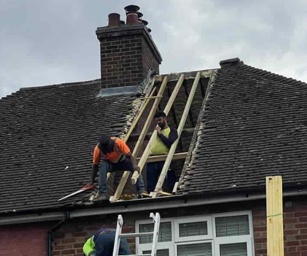 This is a photo of a roof repair being carried out. A section of the roof has been stripped and two roofers are replacing the rafters. Works being carried out by LKN Roofing Shortstown